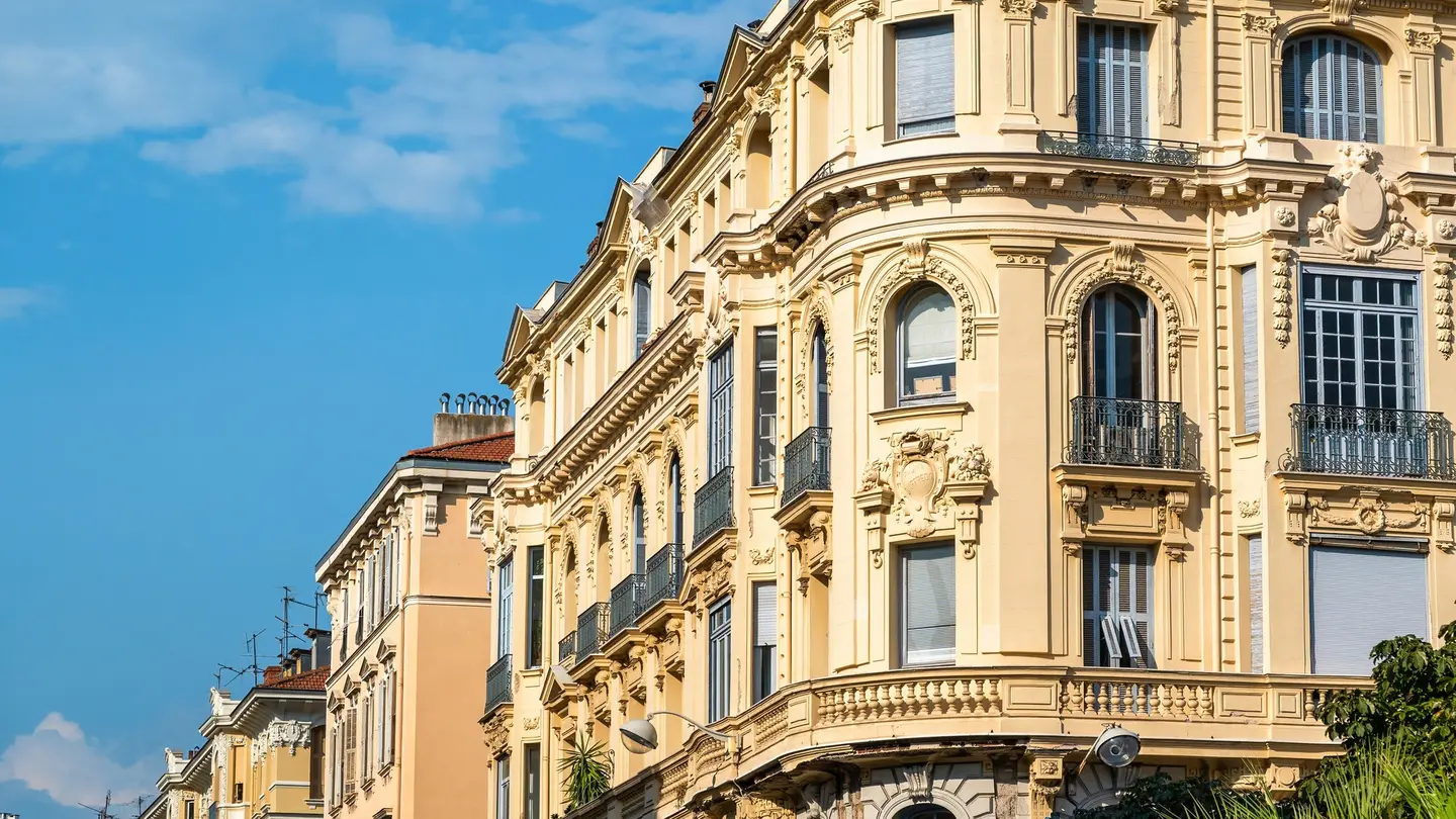 Immeubles anciens aux façades ornées, balcons en fer forgé et volets