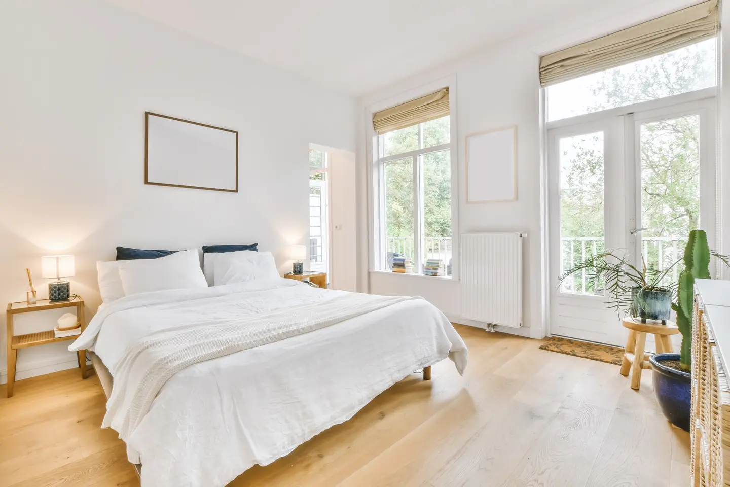 Chambre lumineuse : lit double au linge blanc, parquet clair, hautes fenêtres et porte-fenêtre