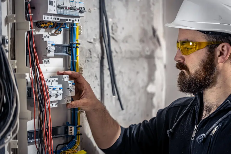 Électricien casqué intervenant sur un tableau électrique