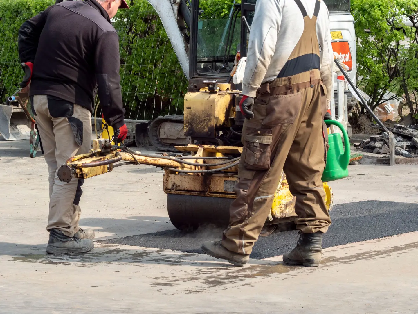 Deux ouvriers compactant un enrobé frais au petit rouleau