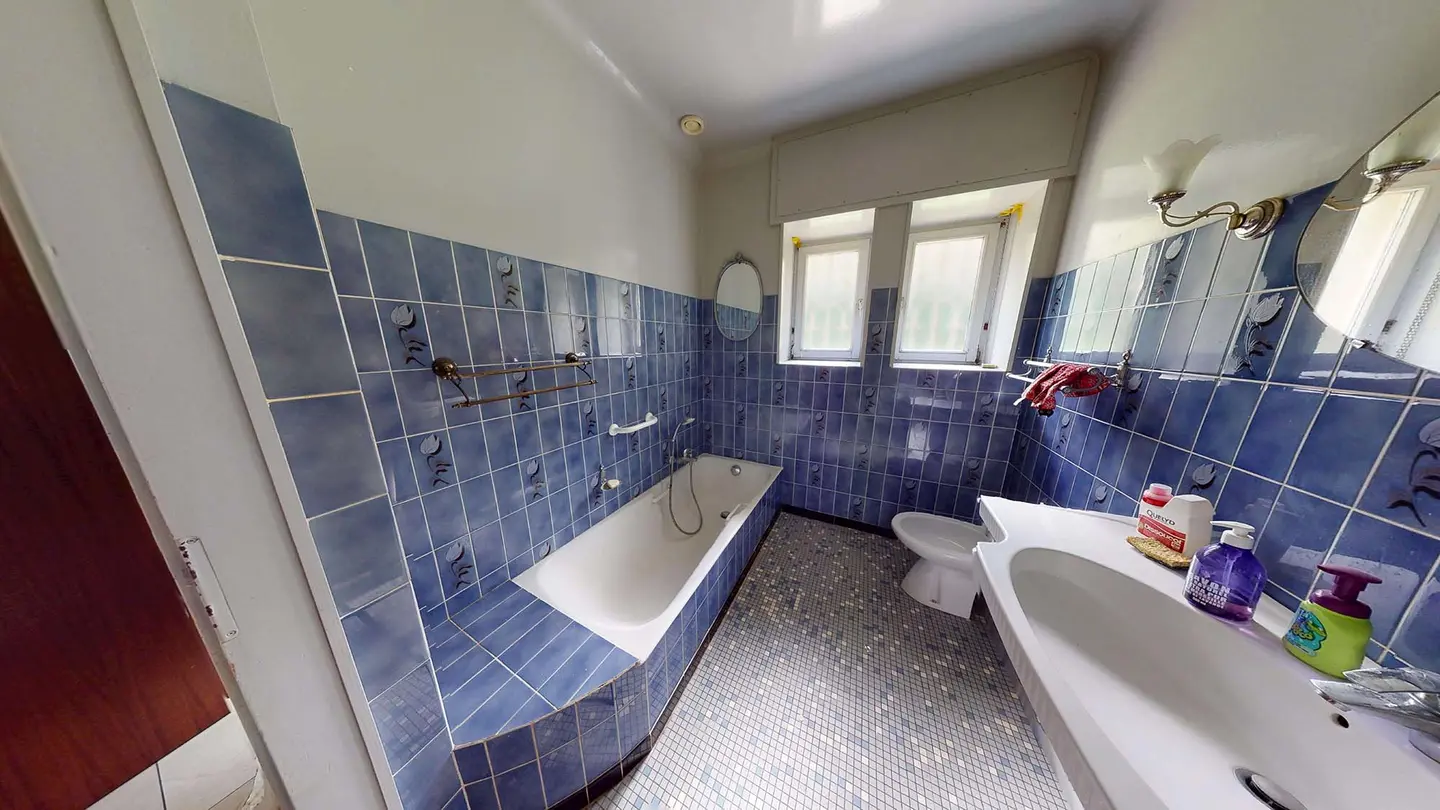 La salle de bain de Plappeville avant travaux : carrelage bleu et baignoire encastrée