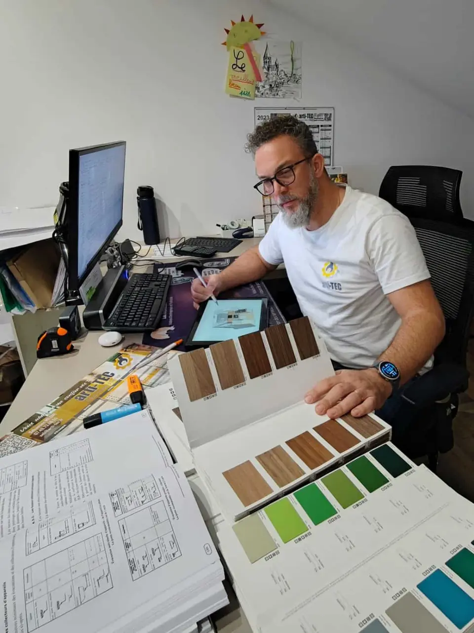 Sébastien Milone à son bureau avec des nuanciers de couleurs et des échantillons de revêtements