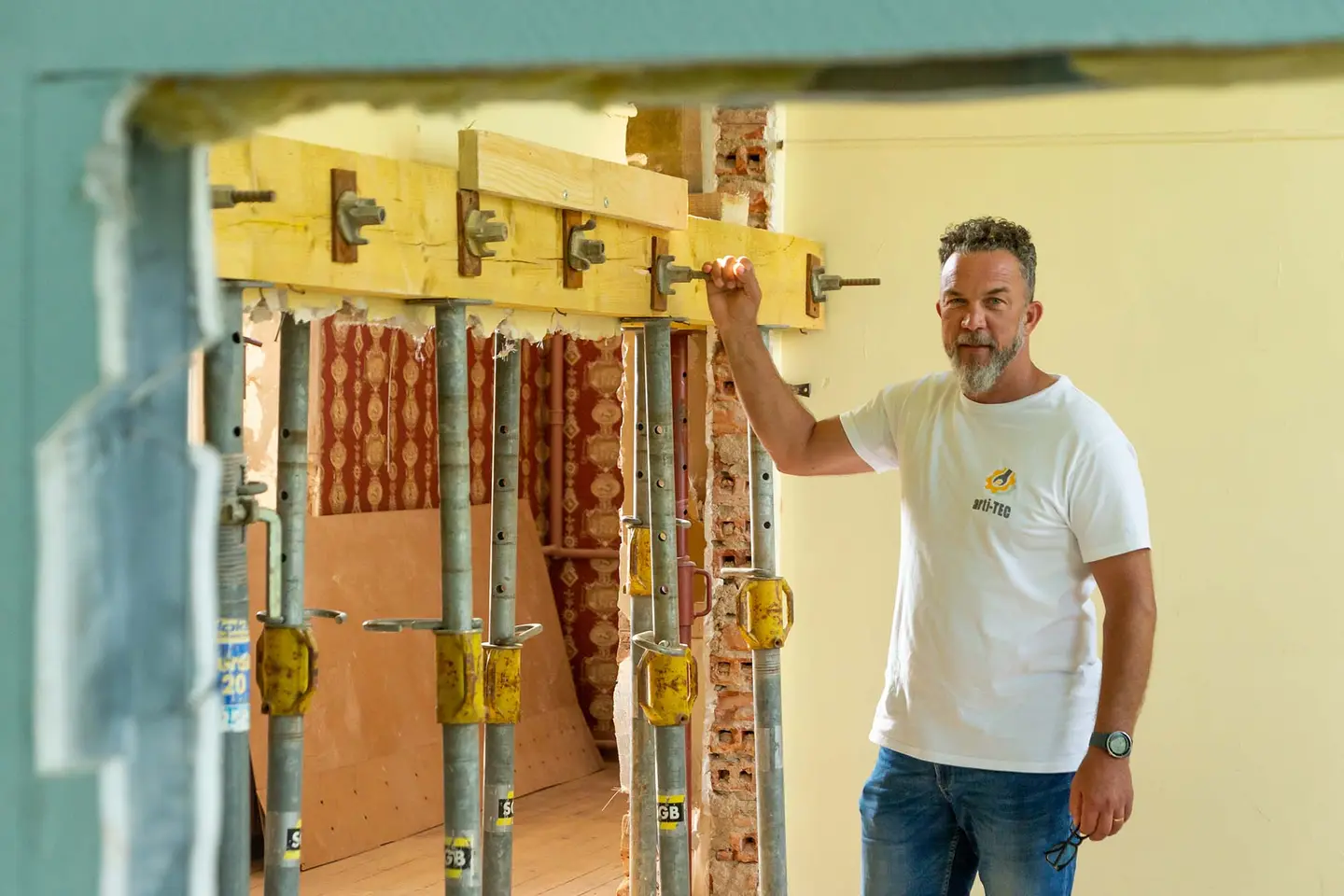 Sébastien Milone, fondateur d'arti-TEC, sur un chantier de rénovation, la main posée sur une poutre soutenue par des étais