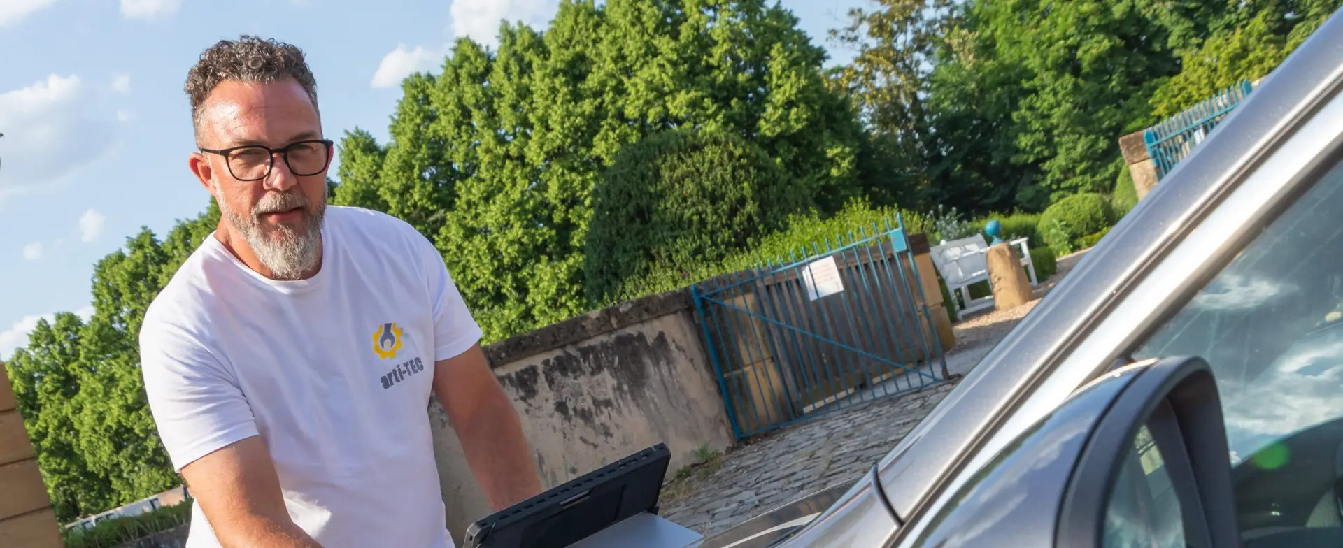 Sébastien Milone, fondateur d'arti-TEC, appuyé sur sa voiture aux couleurs d'arti-TEC